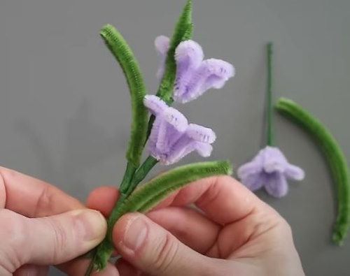 Assembling DIY Pipe Cleaner Starflowers by attaching green leaf shapes